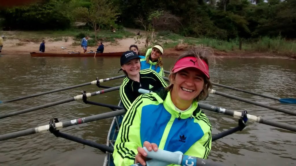 Four smiling masters womens rowers in a quad scull.