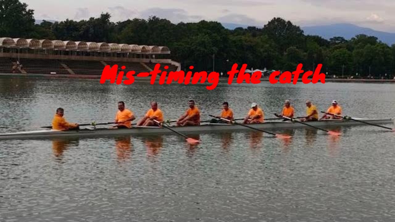 Mens rowing eight crew in orange tshirts on a lake