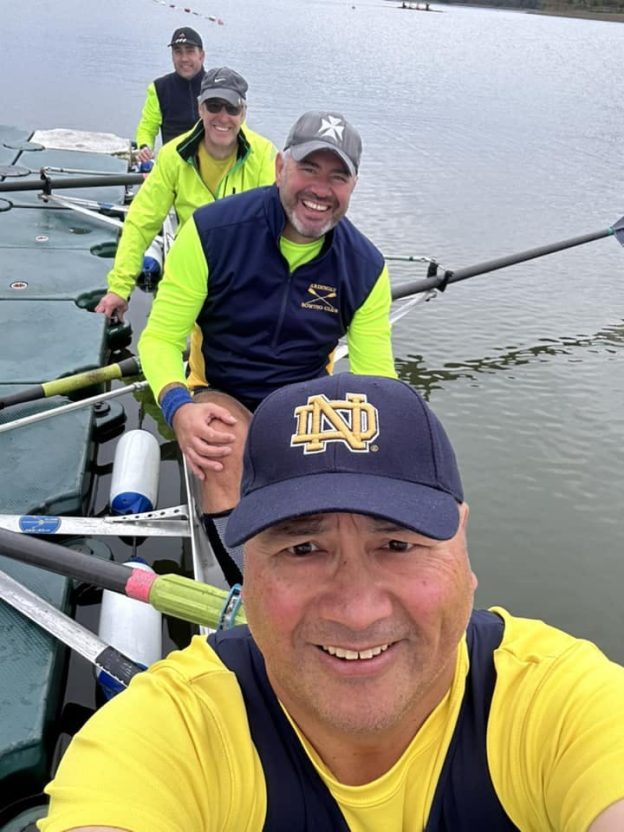 four men wearing yellow shirts in a rowing boat