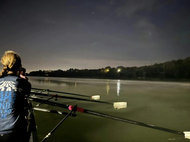 Womens quad rowing boat at night on the river.