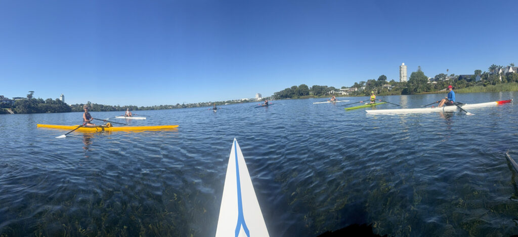 eight single scullers in a circle on Lake Pupuke, New Zealand.